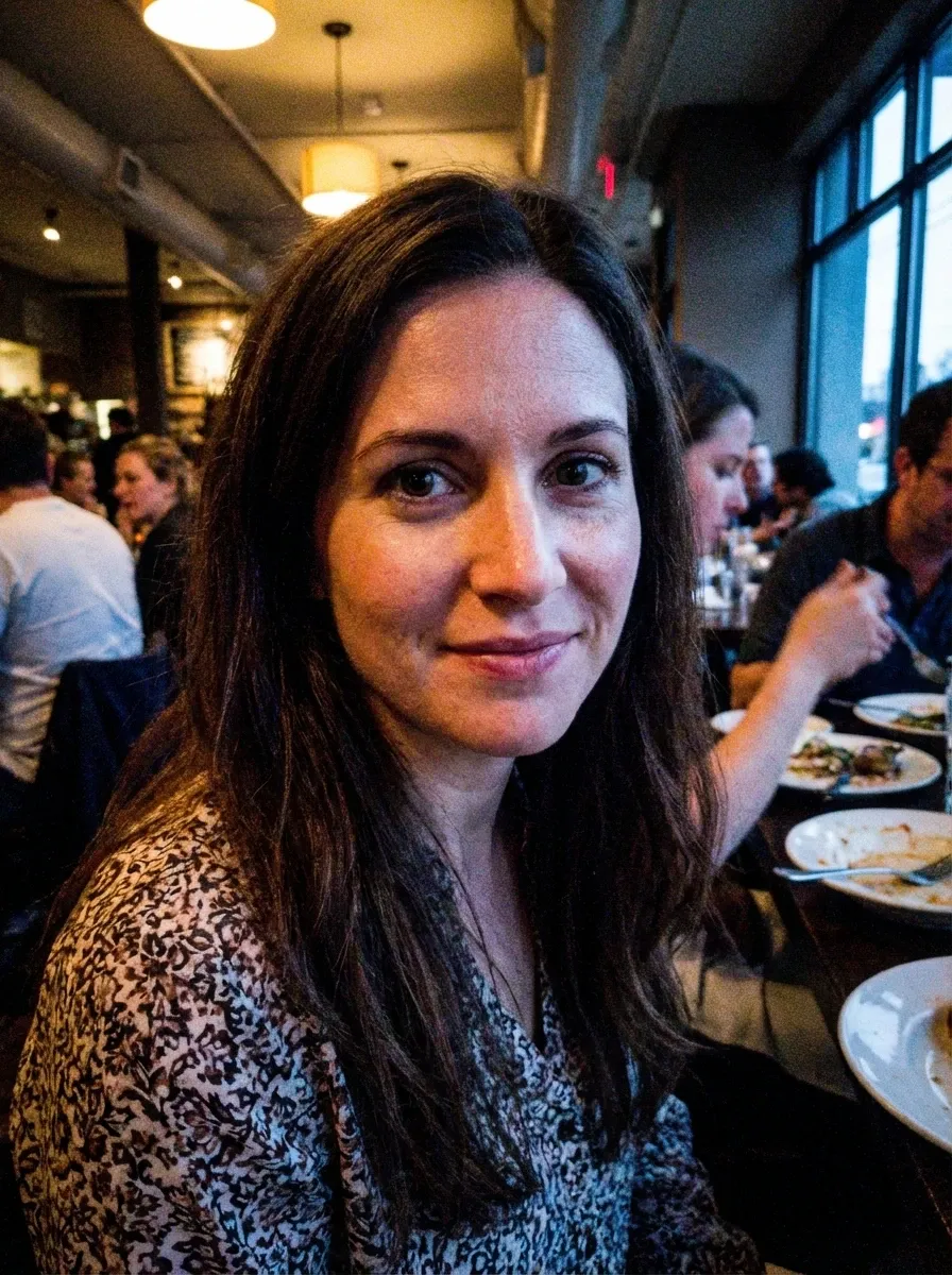 Original selfie input — woman with long dark hair in a patterned top at a restaurant